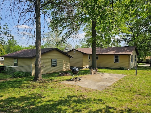 rear view of property featuring a yard, a fire pit, a patio area, and fence