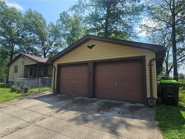 garage featuring fence and concrete driveway