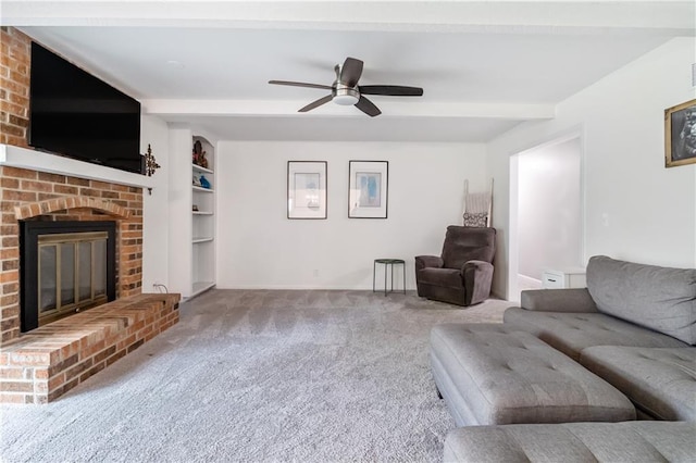 carpeted living room with a ceiling fan, a fireplace, built in shelves, beam ceiling, and baseboards