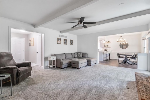 living room with visible vents, carpet flooring, ceiling fan with notable chandelier, and beam ceiling