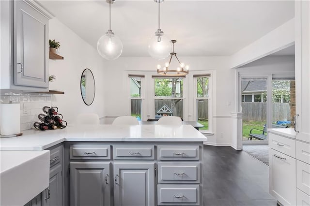 kitchen with light countertops, gray cabinets, a peninsula, and backsplash