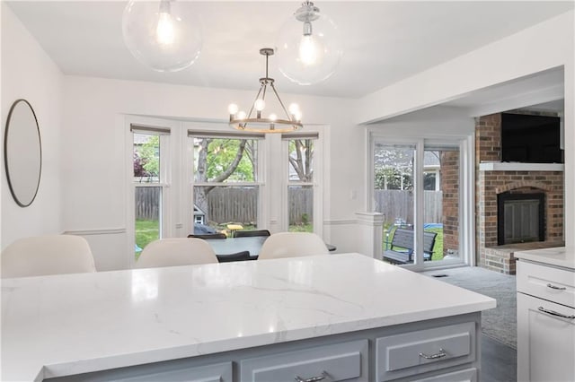 kitchen with light stone countertops, gray cabinetry, plenty of natural light, and an inviting chandelier
