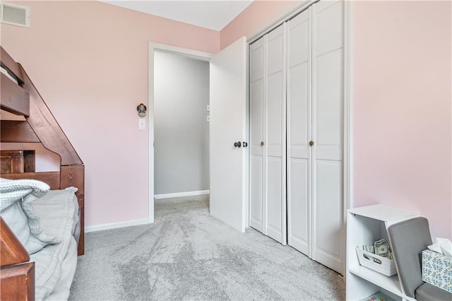 bedroom with baseboards, light colored carpet, visible vents, and a closet