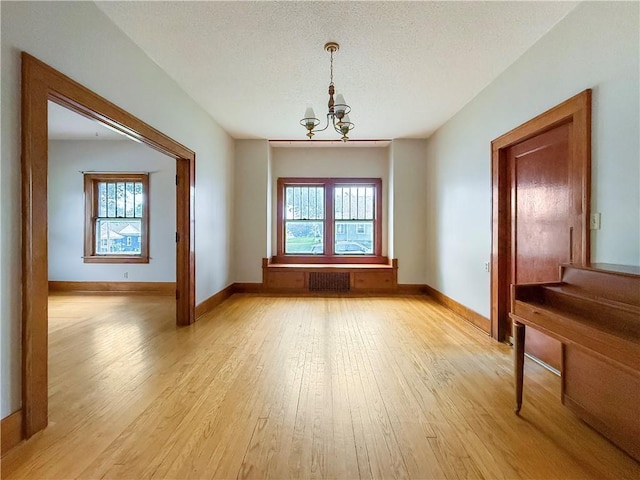 601 W 22nd St, Higginsville, MO 64037 - unfurnished dining area featuring a chandelier, plenty of natural light, light wood-style floors, and a textured ceiling