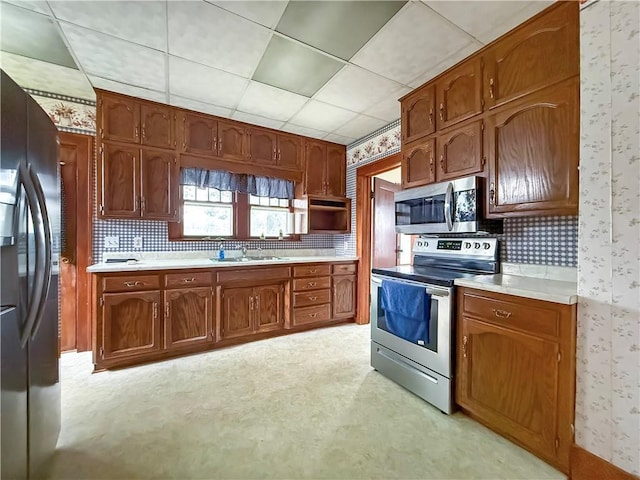 601 W 22nd St, Higginsville, MO 64037 - kitchen with wallpapered walls, appliances with stainless steel finishes, light countertops, brown cabinets, and decorative backsplash