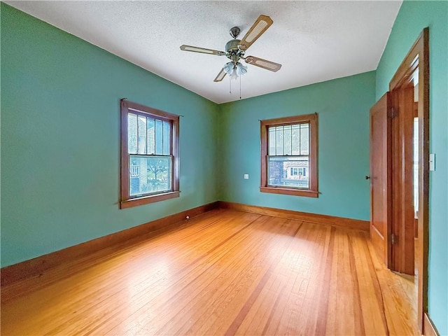 601 W 22nd St, Higginsville, MO 64037 - unfurnished bedroom with light wood finished floors, multiple windows, baseboards, and a textured ceiling
