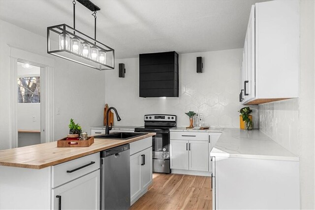 kitchen featuring a sink, butcher block countertops, light wood-style flooring, white cabinetry, and appliances with stainless steel finishes
