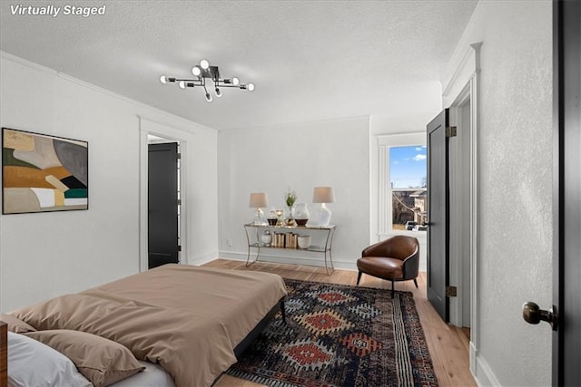 bedroom featuring baseboards, a textured ceiling, crown molding, and light wood-style flooring
