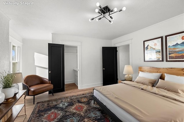 bedroom featuring light wood-style floors, a closet, a walk in closet, baseboards, and a textured ceiling