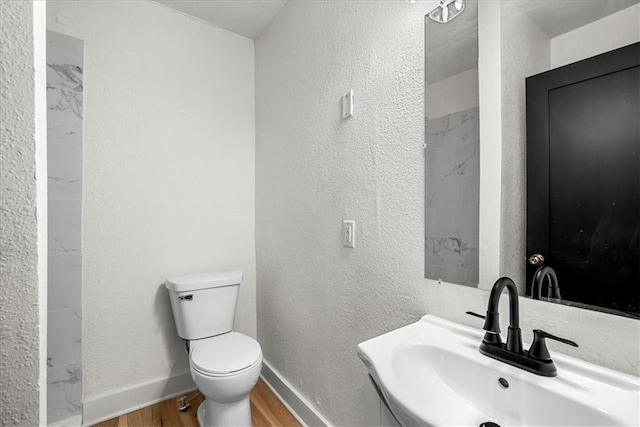bathroom with toilet, a sink, wood finished floors, and baseboards