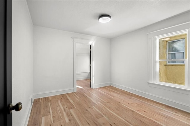 spare room featuring light wood finished floors and baseboards