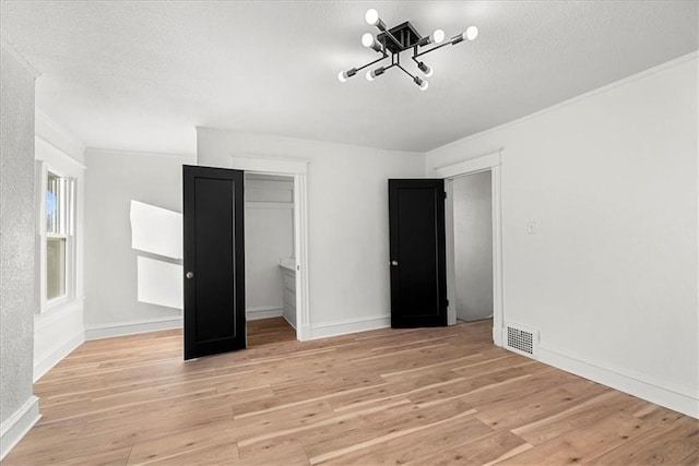 unfurnished bedroom featuring a closet, visible vents, a chandelier, and light wood-type flooring