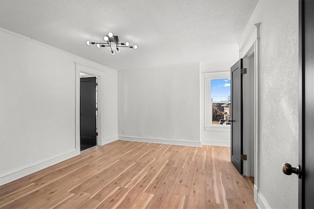 unfurnished bedroom with light wood-style floors, baseboards, a notable chandelier, a textured ceiling, and crown molding
