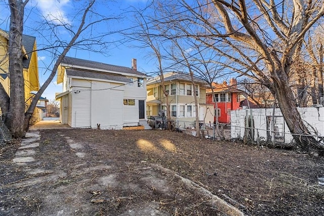 rear view of property with a chimney and fence