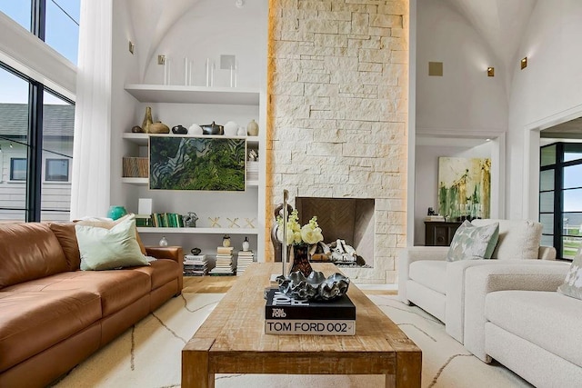living room featuring built in features, a fireplace, wood finished floors, and a towering ceiling