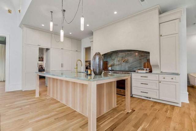 kitchen with a breakfast bar area, recessed lighting, a sink, and light wood-style floors