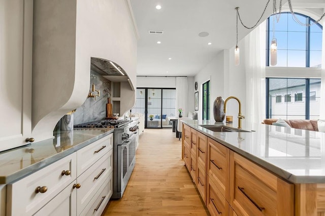 kitchen with visible vents, light wood-type flooring, recessed lighting, range with two ovens, and a sink