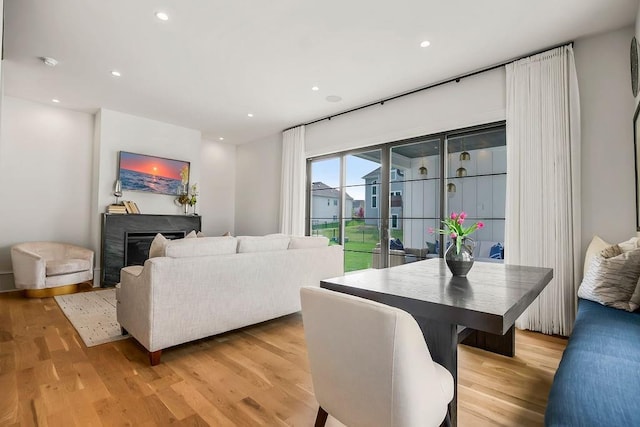 living area featuring a glass covered fireplace, recessed lighting, and light wood-style flooring