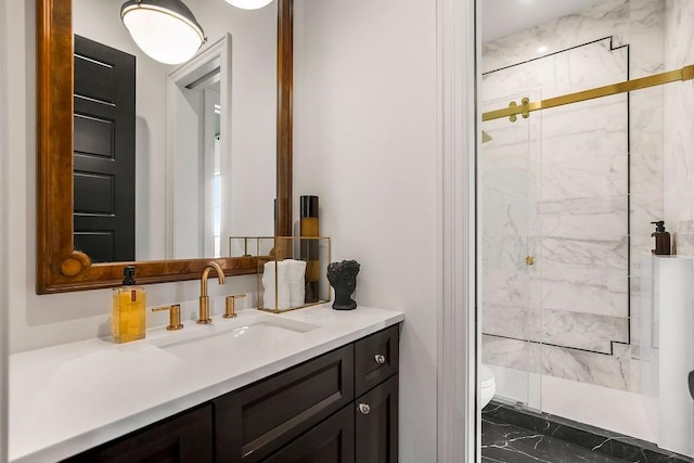 bathroom featuring toilet, a marble finish shower, marble finish floor, and vanity