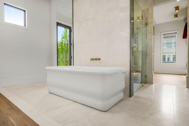 full bathroom featuring a freestanding tub, a stall shower, and tile walls