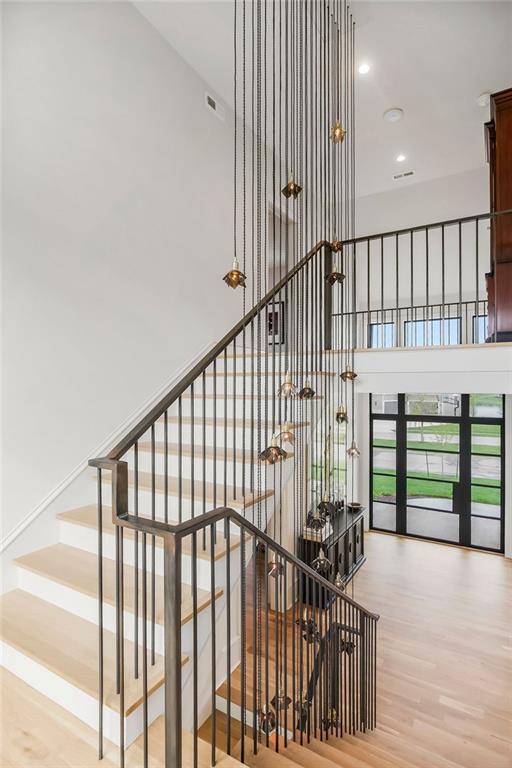 staircase featuring recessed lighting, wood finished floors, and a towering ceiling