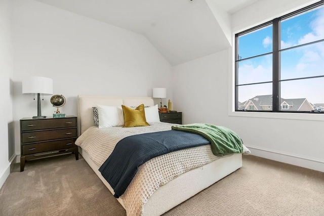 carpeted bedroom featuring baseboards and vaulted ceiling
