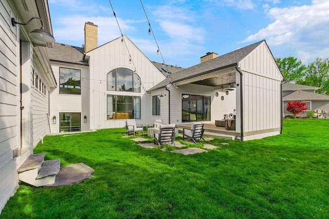back of property featuring an outdoor hangout area, a lawn, board and batten siding, and a chimney