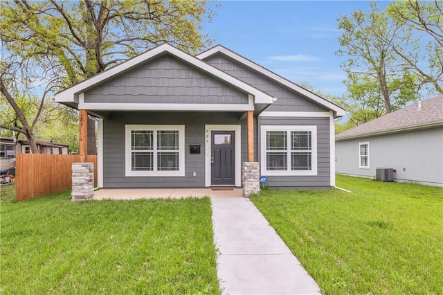bungalow-style home featuring a front lawn, central AC unit, covered porch, and fence