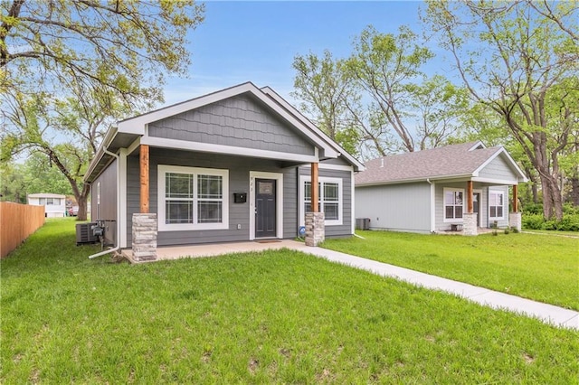 view of front of property with a front yard, fence, and central AC unit