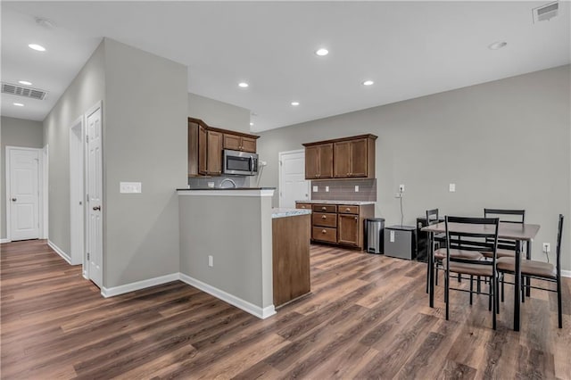 kitchen featuring dark wood-style flooring, stainless steel microwave, and visible vents
