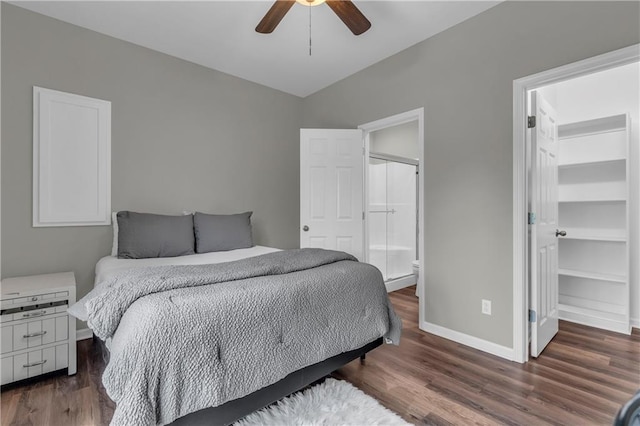 bedroom featuring wood finished floors, a walk in closet, ensuite bath, and baseboards