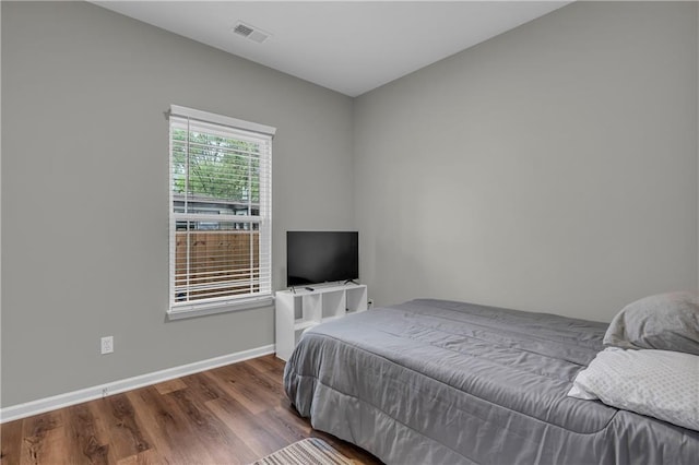 bedroom with visible vents, wood finished floors, and baseboards