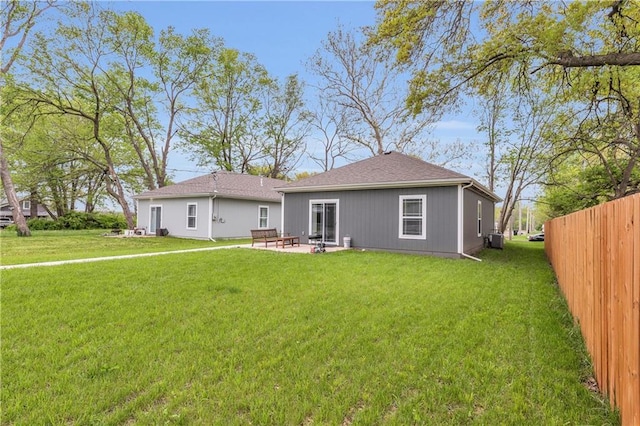 back of property with fence, a yard, a patio area, and central AC
