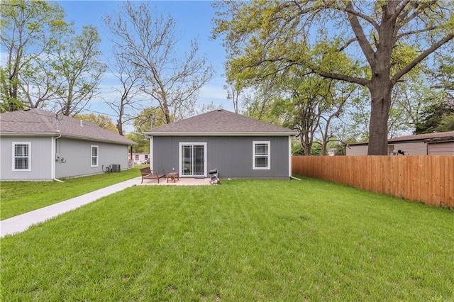 rear view of property featuring fence, a yard, and a patio