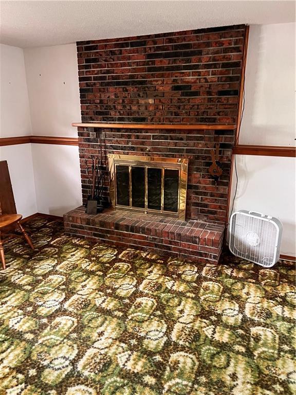 unfurnished living room featuring a brick fireplace and a textured ceiling