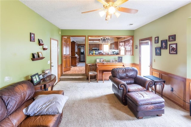 living room with carpet flooring, wainscoting, a textured ceiling, and ceiling fan