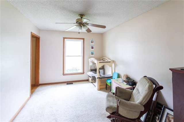 sitting room with a ceiling fan, carpet flooring, a textured ceiling, and baseboards