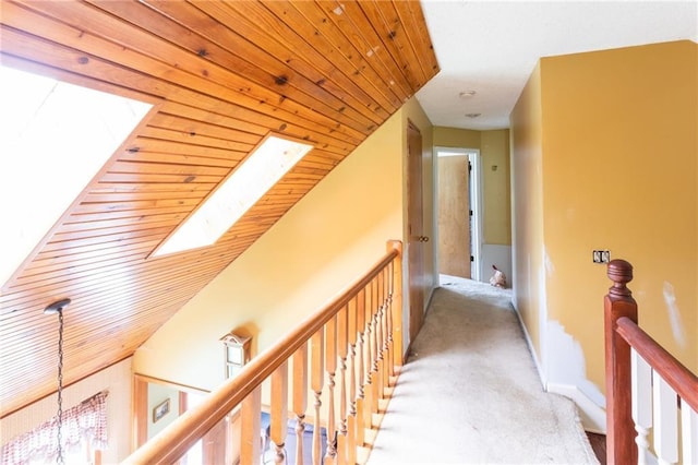 corridor with a skylight, an upstairs landing, carpet flooring, and a chandelier