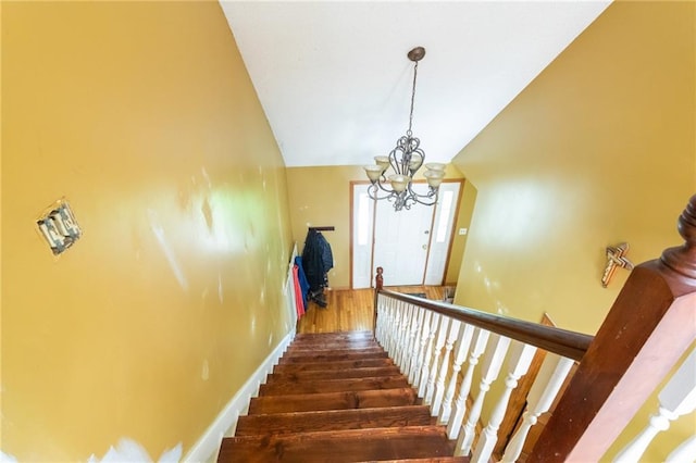 stairway featuring a chandelier, wood finished floors, and vaulted ceiling