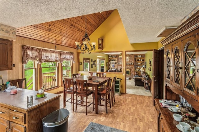 dining space with light wood-type flooring, a chandelier, a textured ceiling, and high vaulted ceiling