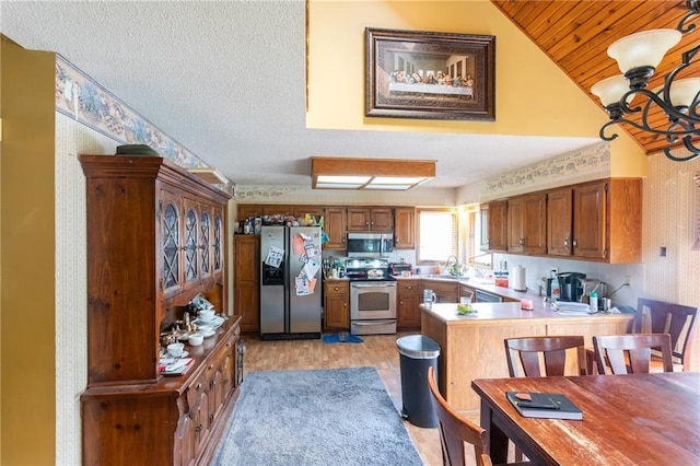 kitchen with stainless steel appliances, a peninsula, a sink, vaulted ceiling, and light countertops