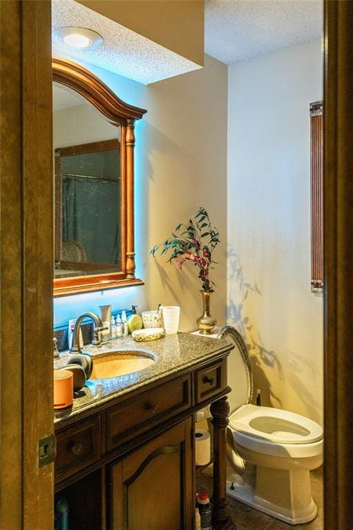 full bathroom featuring a textured ceiling, toilet, and vanity