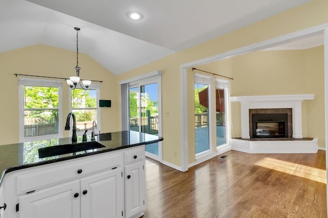 kitchen featuring a sink, white cabinets, pendant lighting, and wood finished floors