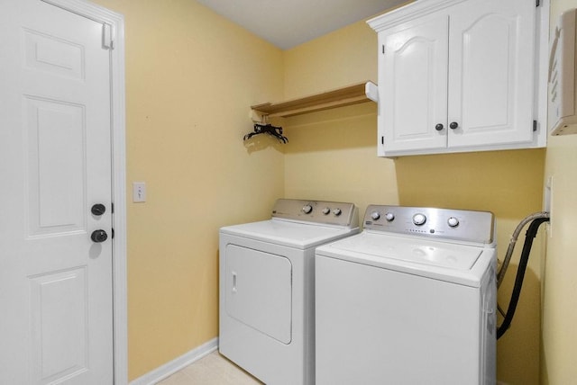 washroom with baseboards, cabinet space, and washing machine and dryer