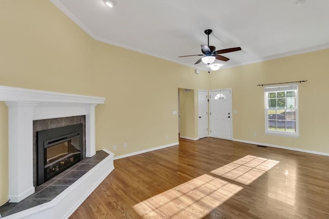 unfurnished living room with a fireplace, a ceiling fan, wood finished floors, visible vents, and ornamental molding