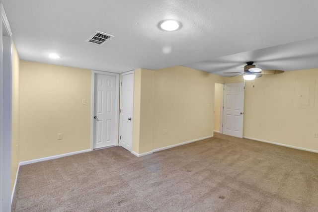 carpeted spare room with visible vents, a ceiling fan, baseboards, and a textured ceiling