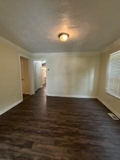 empty room featuring dark wood finished floors, baseboards, visible vents, and crown molding
