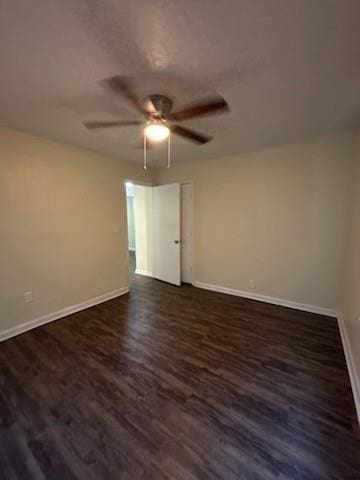 unfurnished room with dark wood-style floors, a ceiling fan, and baseboards