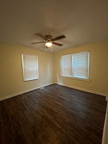 unfurnished room with dark wood-style floors, a ceiling fan, and baseboards