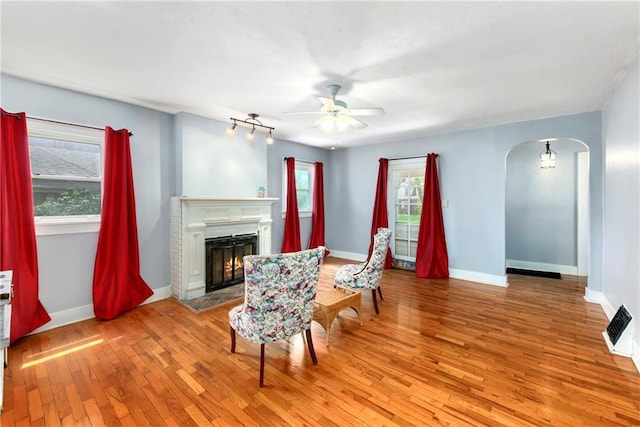 314 N Lake St, Pleasant Hill, MO 64080 - living area featuring a ceiling fan, arched walkways, baseboards, light wood finished floors, and a warm lit fireplace